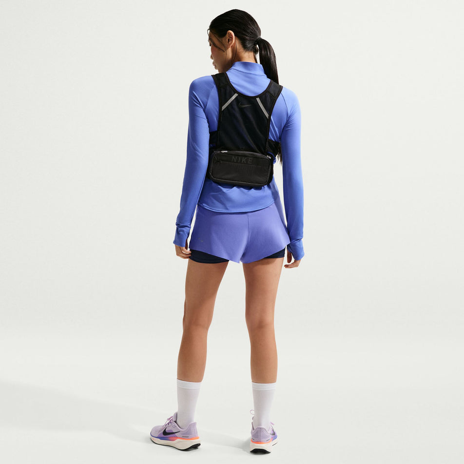 Back view of a model wearing the Nike Women's Swift Dri-FIT Mid-Rise 2-in-1 Running Shorts in the Sapphire/Midnight Navy/Reflective Silver colourway.