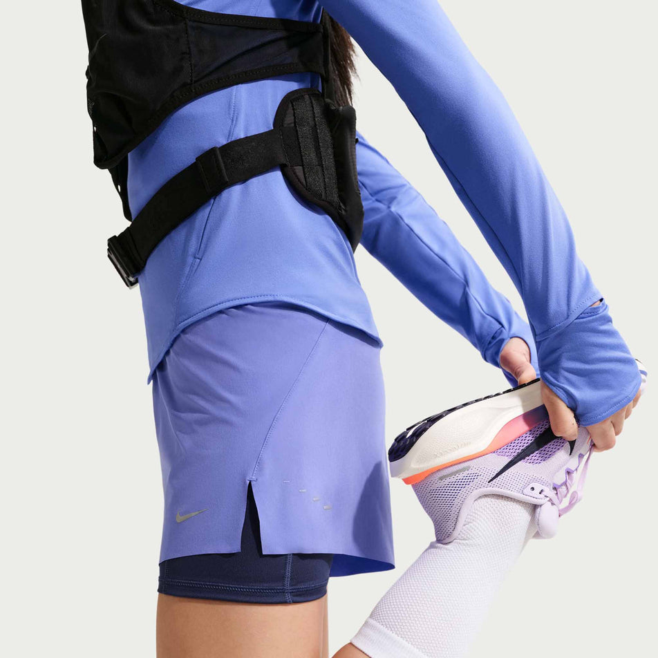 Side view of a model wearing the Nike Women's Swift Dri-FIT Mid-Rise 2-in-1 Running Shorts in the Sapphire/Midnight Navy/Reflective Silver colourway.