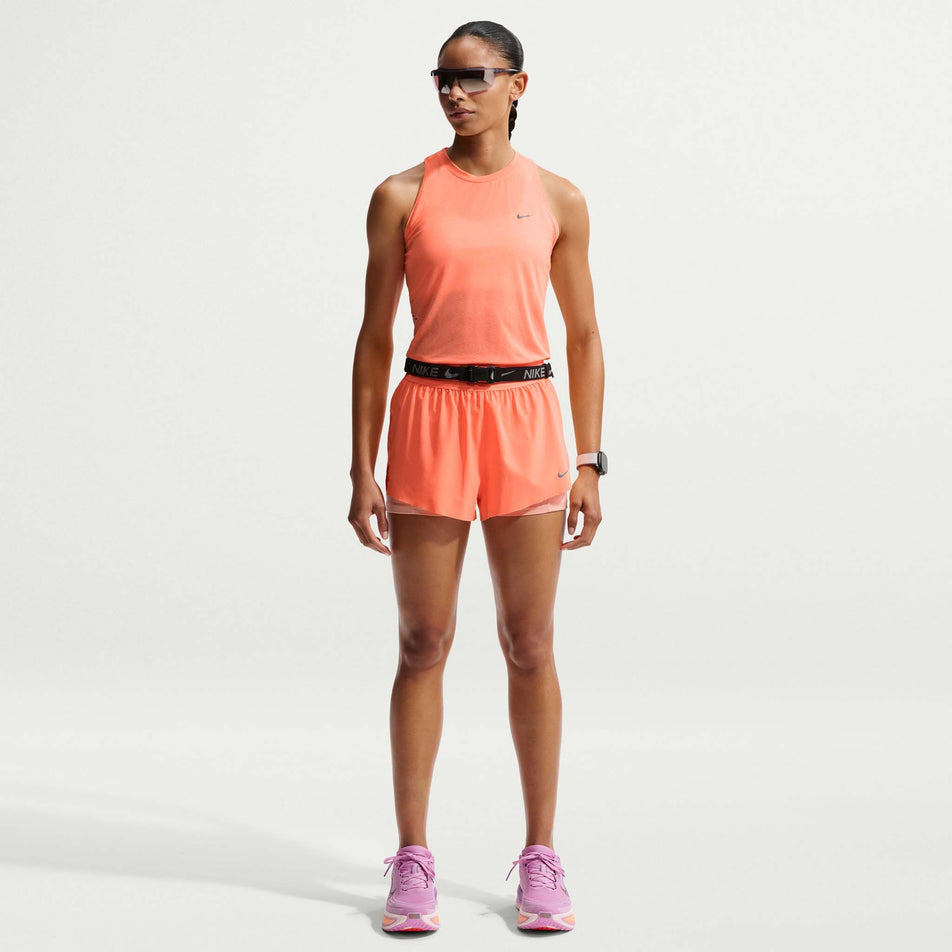 Front view of a model wearing the Nike Women's Swift Dri-FIT Mid-Rise 2-in-1 Running Shorts in the Orange Pulse/Reflective Silver colourway.