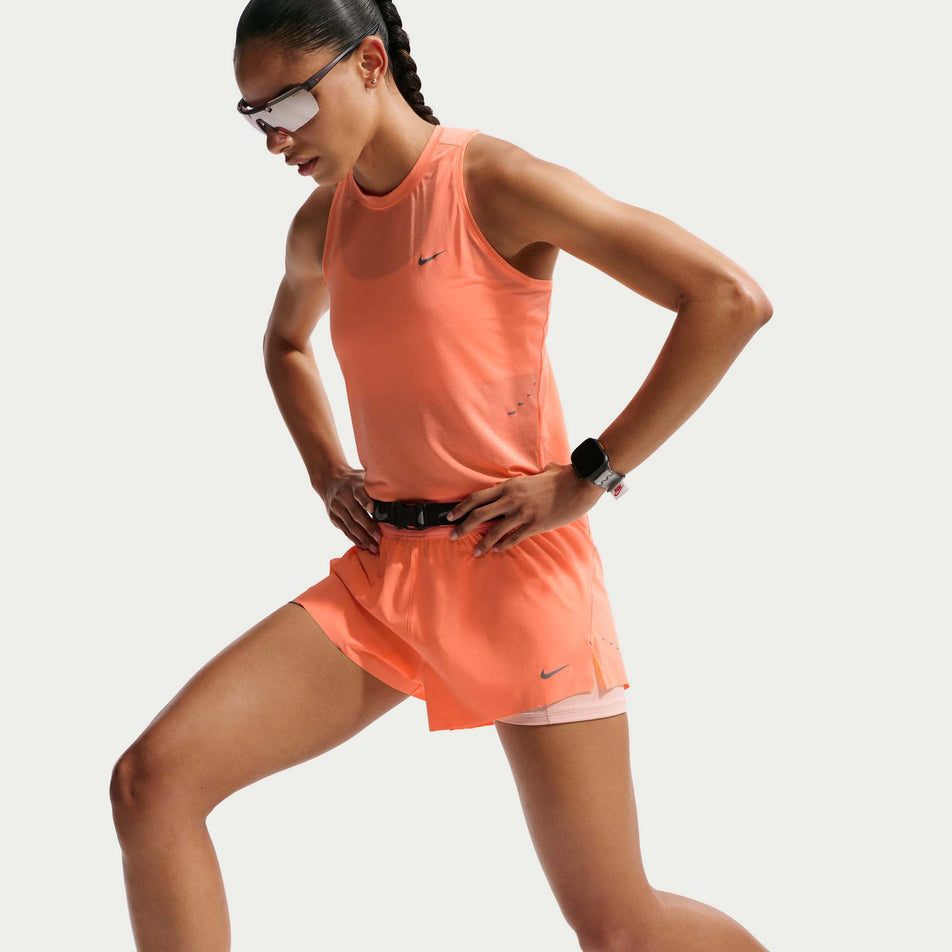 Angled view of a model wearing the Nike Women's Swift Dri-FIT Mid-Rise 2-in-1 Running Shorts in the Orange Pulse/Reflective Silver colourway.