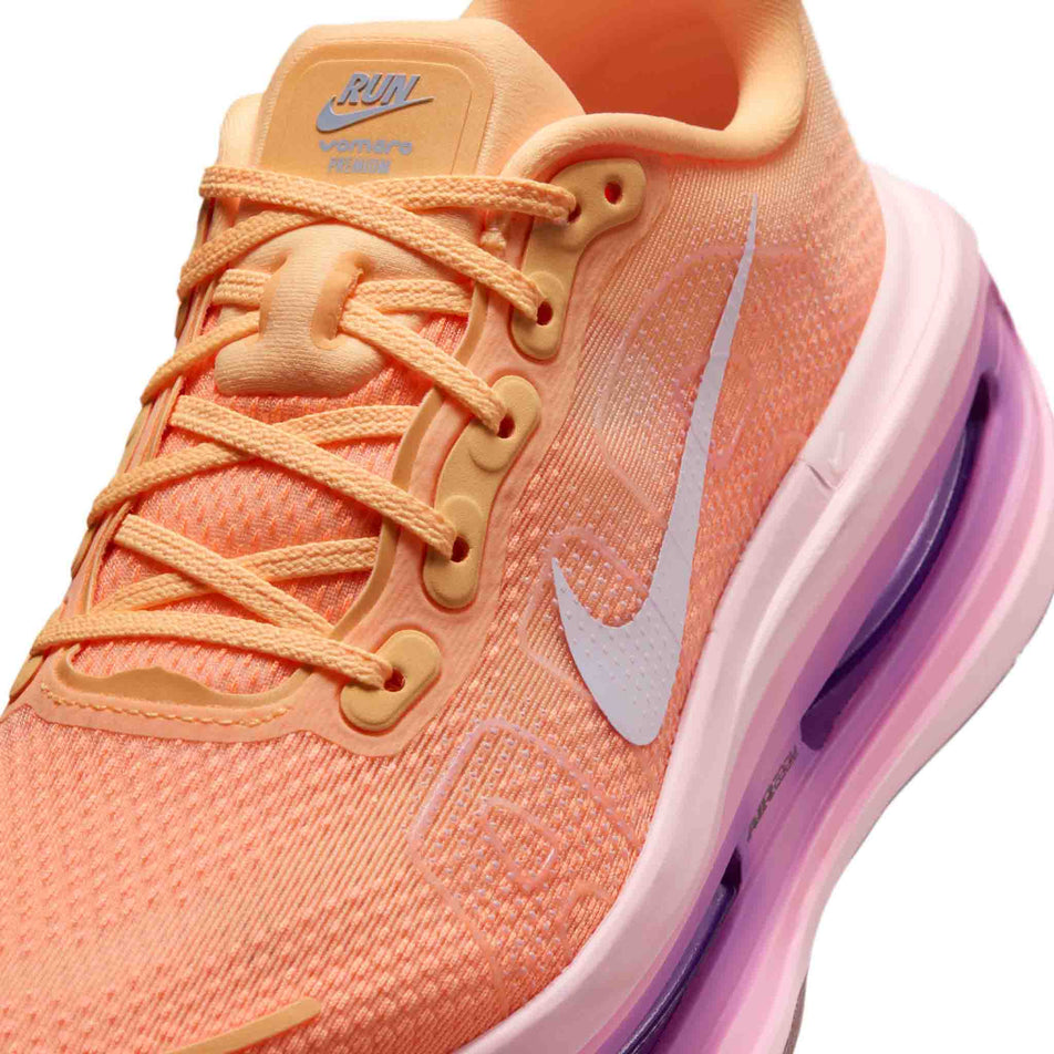 Close-up view of the upper of the left shoe from a pair of Nike Women's Vomero Premium Road Running Shoes in the Tangerine Tint/Tattoo-Bright Crimson colourway.
