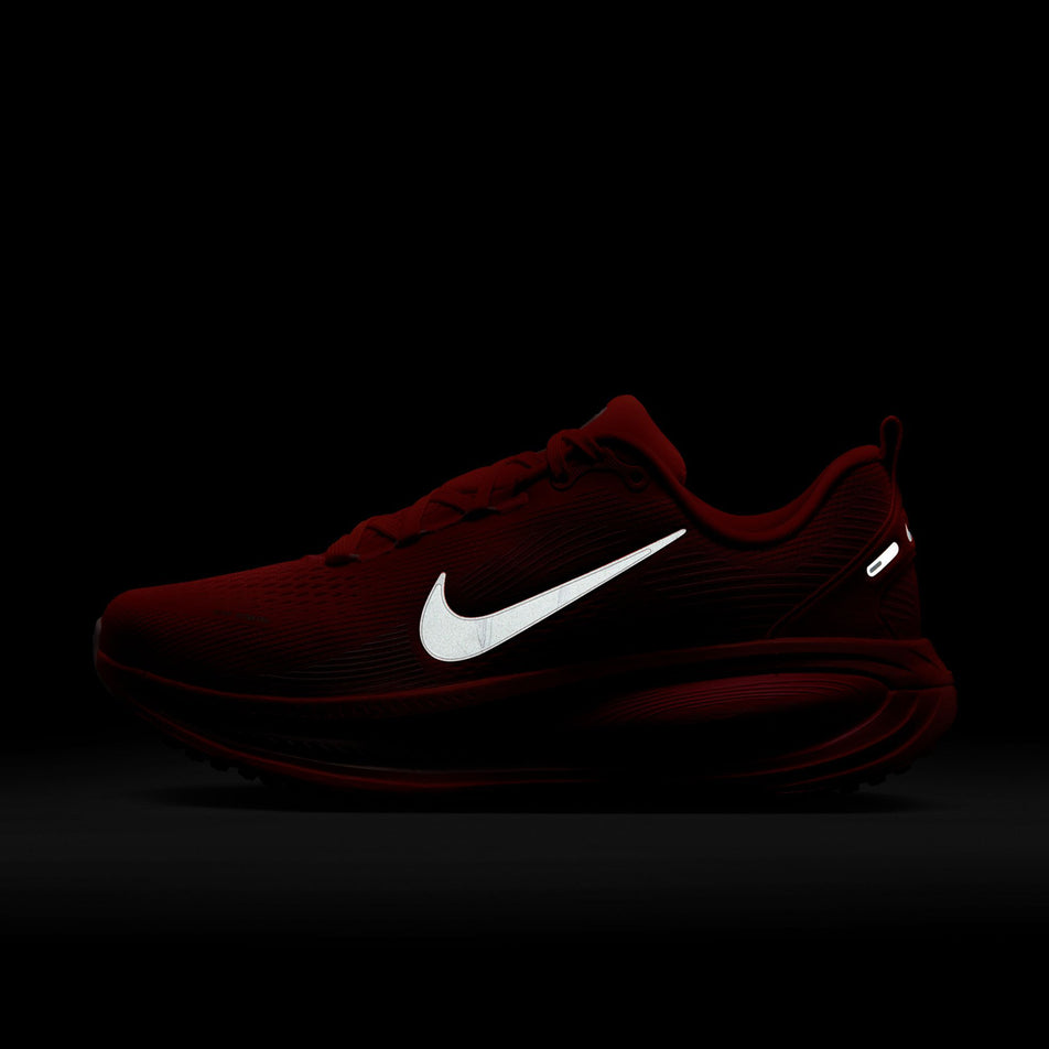 The reflective Nike swoosh on the lateral side of the left shoe from a pair of Nike Women's Vomero 18 Road Running Shoes in the Bright Crimson/White-Hyper Pink colourway. (8686791786658)