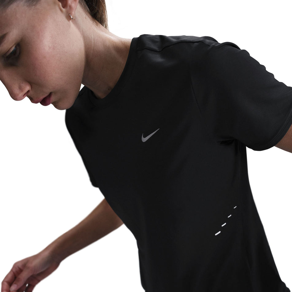 Angled front view of a model wearing a Nike Women's Swift Dri-FIT Short-Sleeve Running Top in the Black/Reflective Silver colourway. (8560479404194)