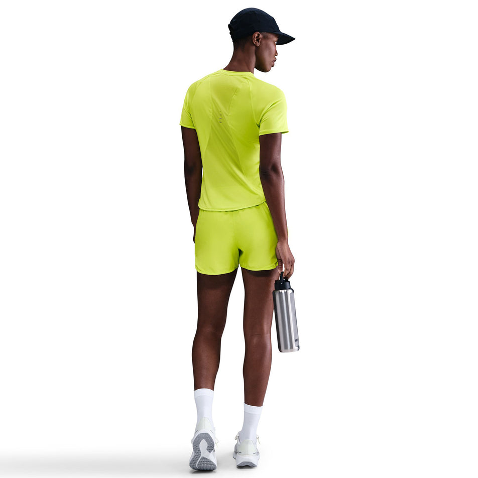 Back view of a model wearing the Nike Women's Swift Dri-FIT Short-Sleeve Running Top in the Cyber/Reflective Silver colourway. (8756557775010)