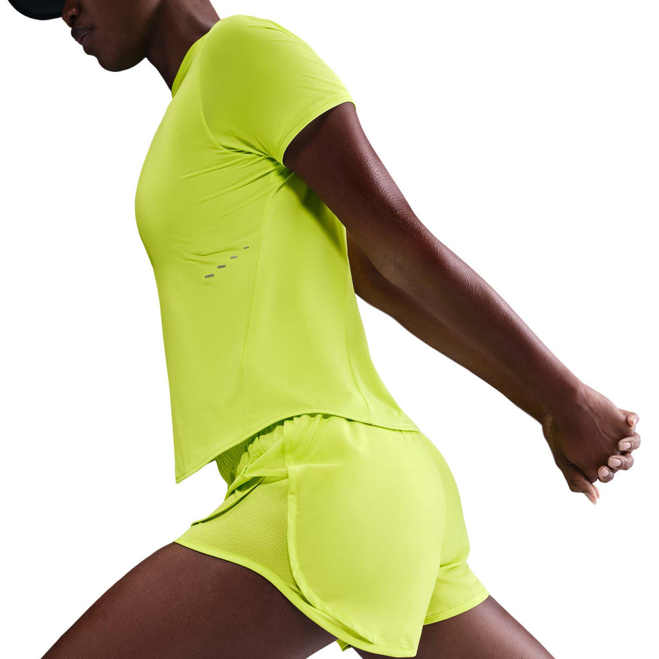 Side view of a model wearing the Nike Women's Swift Dri-FIT Short-Sleeve Running Top in the Cyber/Reflective Silver colourway. (8756557775010)