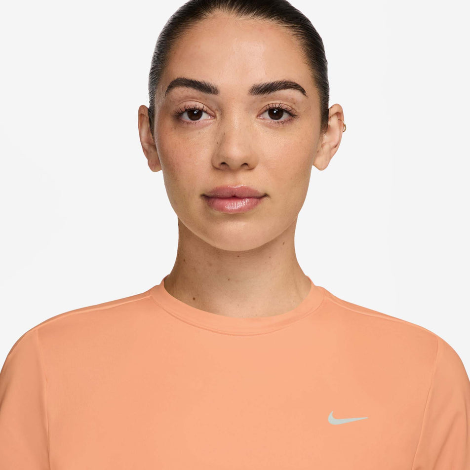 Front view of a model wearing the Nike Women's Swift Dri-FIT Short-Sleeve Running Top in the Orange Pulse/Reflective Silver colourway.
