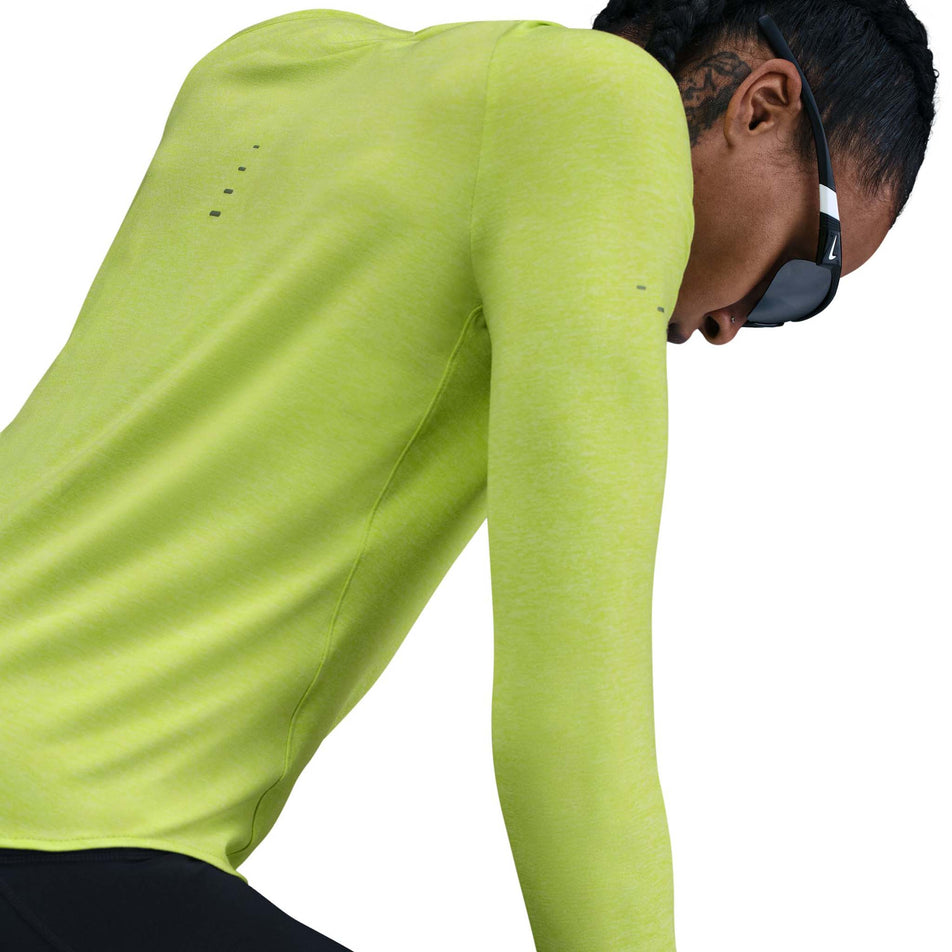 Angled view of a model wearing the Nike Women's Swift Dri-FIT UV Long-Sleeve Crew-Neck Running Top in the Cyber/Heather/Reflective Silver colourway. (8756573110434)