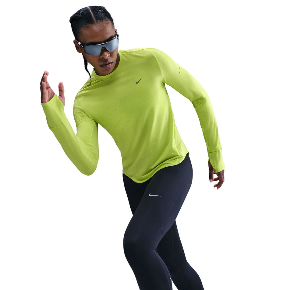 Angled view of a model wearing the Nike Women's Swift Dri-FIT UV Long-Sleeve Crew-Neck Running Top in the Cyber/Heather/Reflective Silver colourway. (8756573110434)