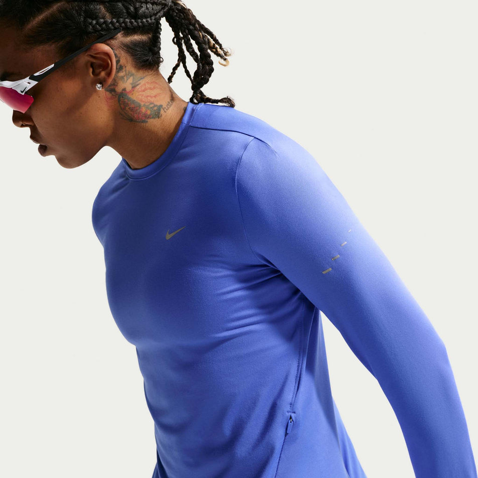 Angled view of a model wearing the Nike Women's Swift Dri-FIT UV Long-Sleeve Crew-Neck Running Top in the Sapphire/Reflective Silver colourway.