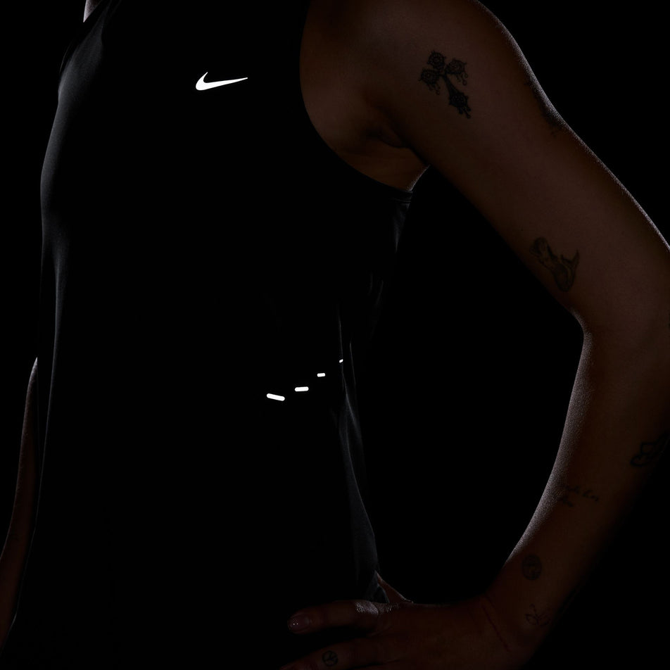 The reflective Nike SWOOSH and reflective graphics on the front of a Nike Women's Swift Dri-FIT Running Tank Top in the Black/Reflective Silver colourway. (8560470524066)