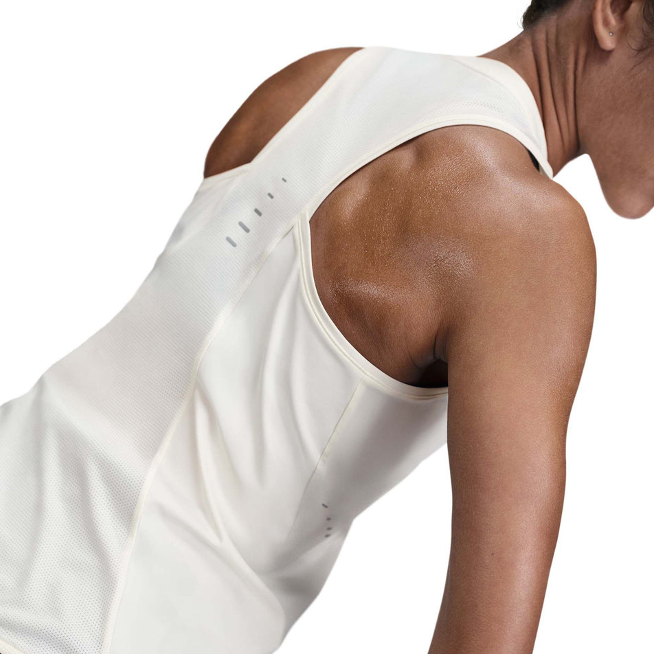 Back view of a model wearing the Nike Women's Swift Dri-FIT Running Tank Top in the Sail/Reflective Silver colourway. (8692446134434)