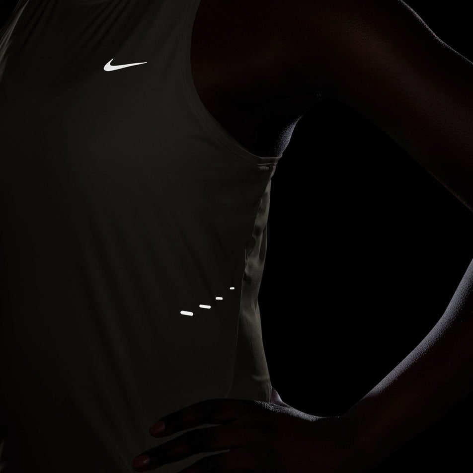The reflective Nike Swoosh and pills on the Nike Women's Swift Dri-FIT Running Tank Top in the Sail/Reflective Silver colourway.(8692446134434)