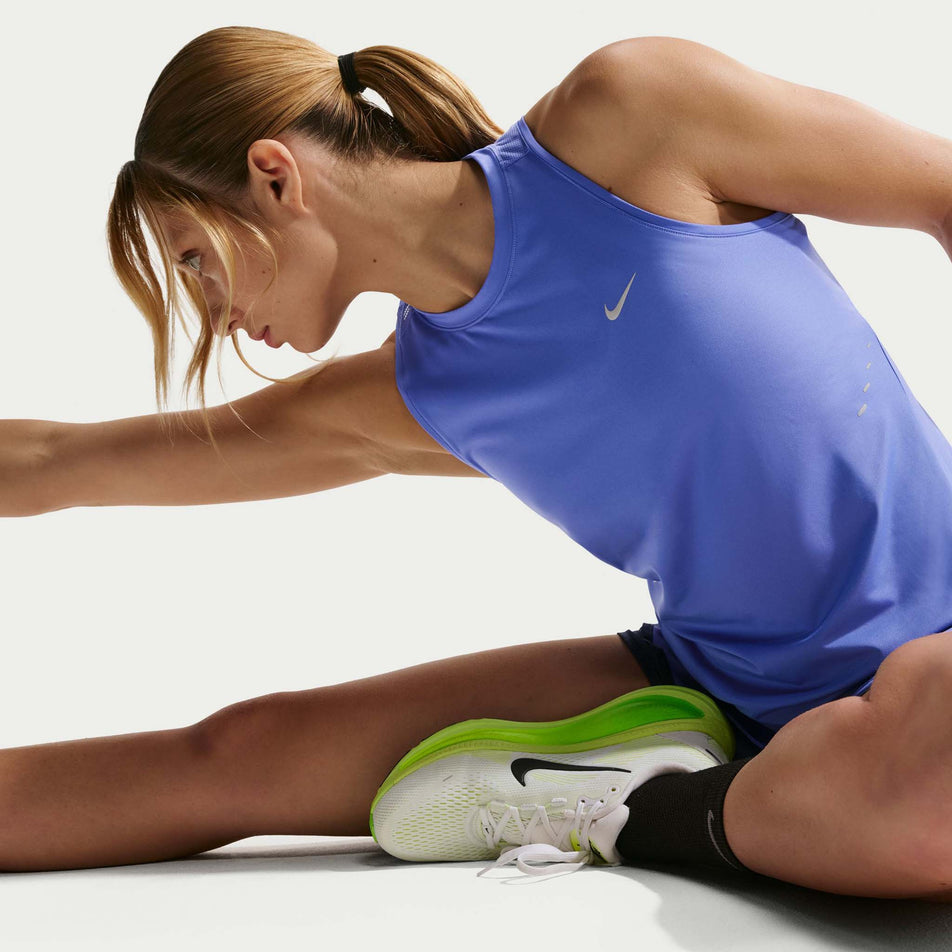 Angled view of a model wearing the Nike Women's Swift Dri-FIT Running Tank Top in the Sapphire/Reflective Silver colourway.