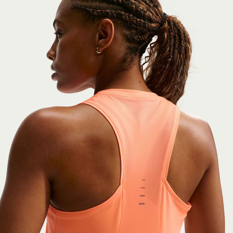 Back view of a model wearing the Nike Women's Swift Dri-FIT Running Tank Top in the Orange Pulse/Reflective Silver colourway.
