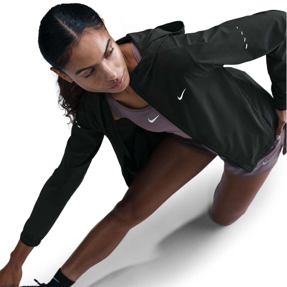 Angled view of a model wearing a Nike Women's Swift Repel Packable Running Jacket in the Black/Reflective Silver colourway. (8560817635490)