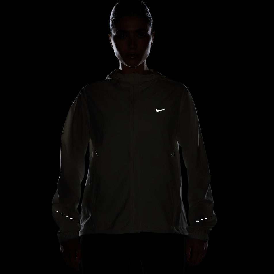 The reflective Swoosh and reflective pills on the Nike Women's Swift Repel Packable Running Jacket in the Sail/Reflective Silver colourway. (8732499738786)