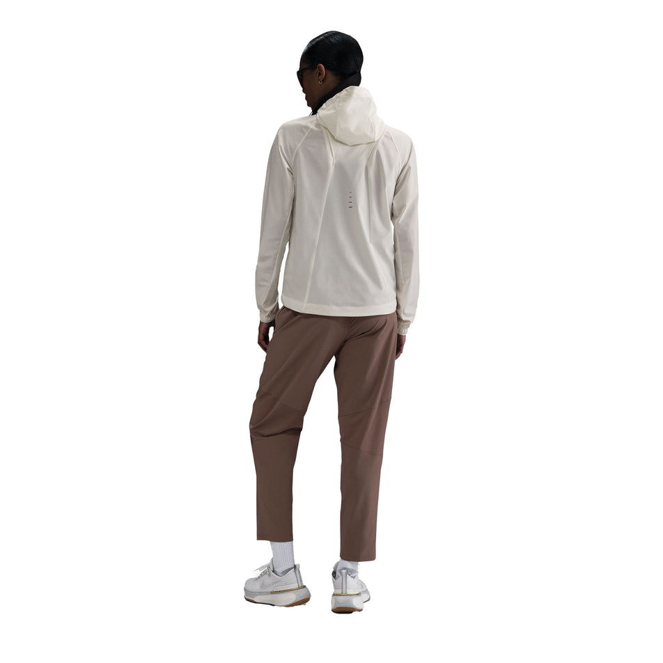 Back view of a model wearing the Nike Women's Swift Repel Packable Running Jacket in the Sail/Reflective Silver colourway. (8732499738786)
