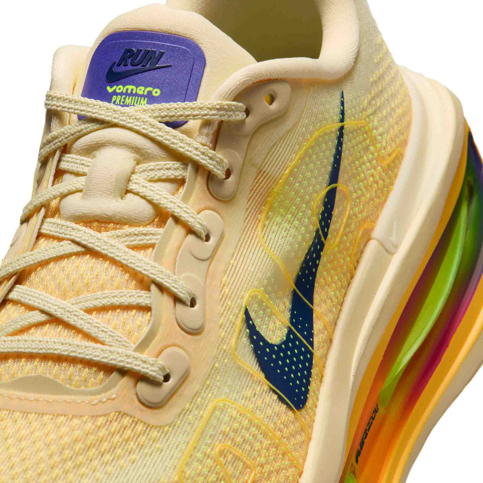 Close-up view of the upper of the left shoe from a pair of Nike Men's Vomero Premium Road Running Shoes in the Alabaster/Blue Void-Citron Pulse colourway.