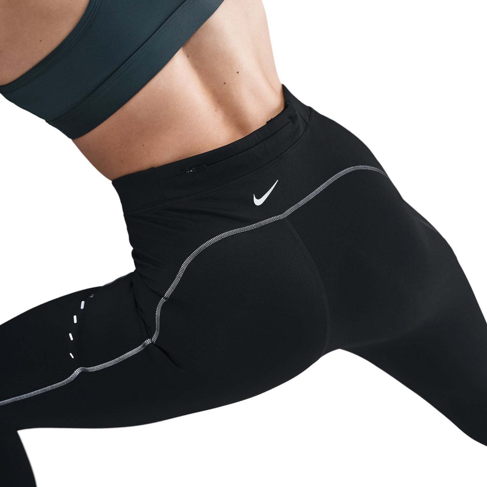 Back view of a model wearing the Nike Women's Swift High-Waisted 7/8 Running Leggings in the Black/Dark Smoke Grey colourway. (8756531626146)