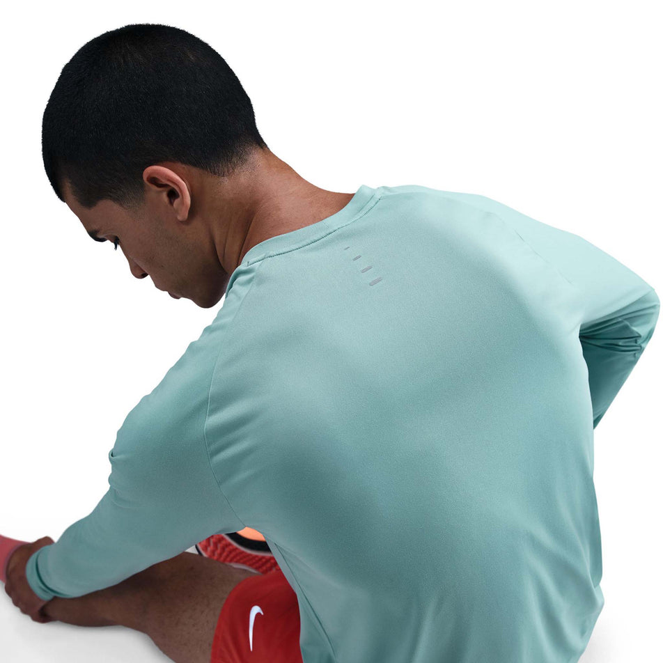 Angled view of a model wearing the Nike Men's Stride Dri-FIT ADV Long-Sleeve Running Top in the Cannon/Reflective Silver colourway. (8778197172386)
