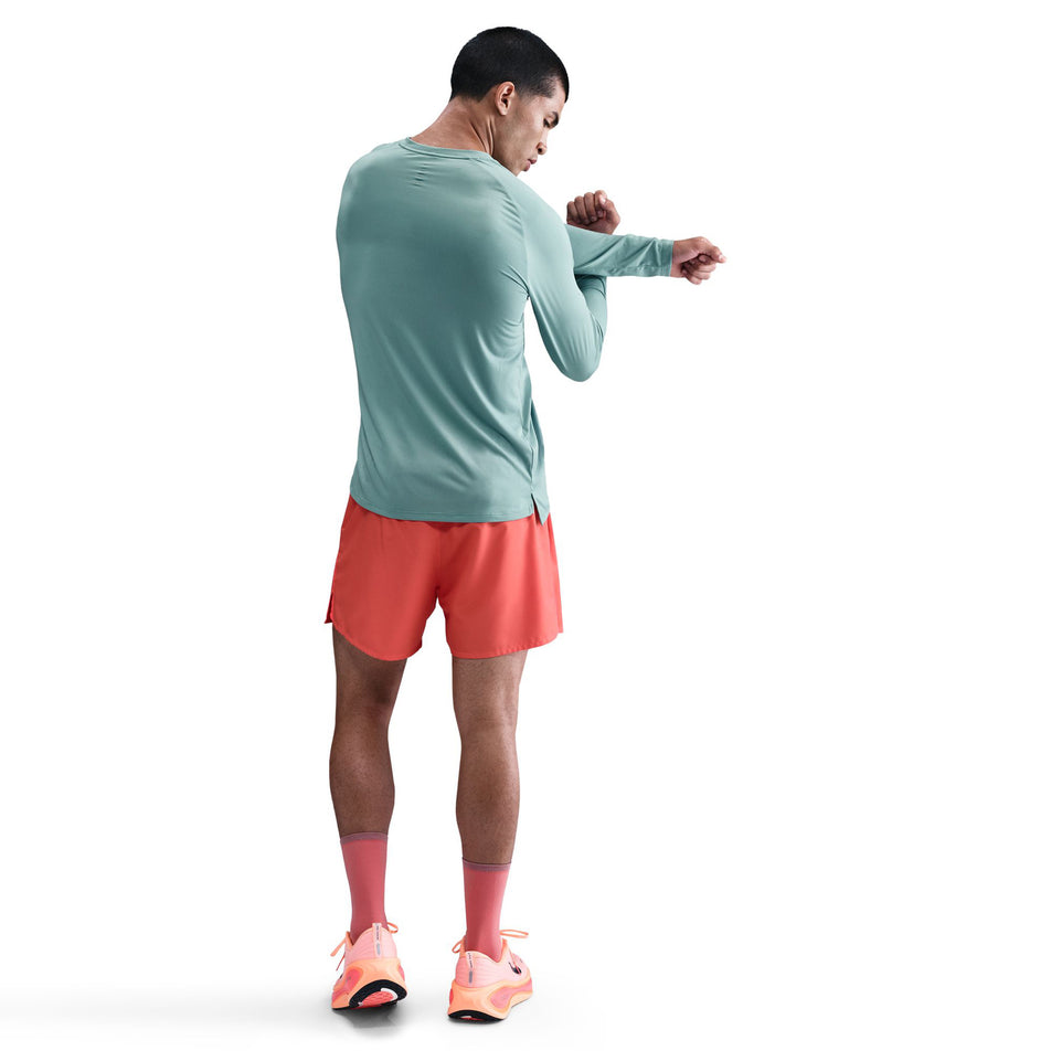 Back view of a model wearing the Nike Men's Stride Dri-FIT ADV Long-Sleeve Running Top in the Cannon/Reflective Silver colourway. (8778197172386)