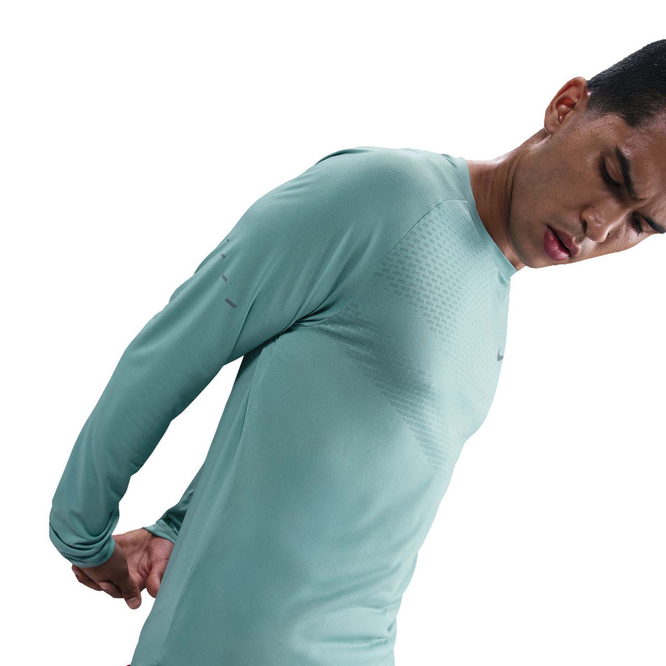 Angled view of a model wearing the Nike Men's Stride Dri-FIT ADV Long-Sleeve Running Top in the Cannon/Reflective Silver colourway. (8778197172386)