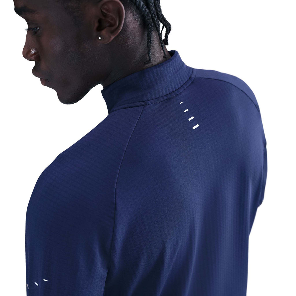Angled view of a model wearing the Nike Men's Stride Therma-FIT Repel Winterized 1/2-Zip Running Top in the Blue Void/Reflective Silver colourway. (8778201989282)