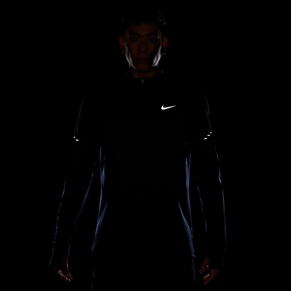 The reflective Swoosh logo and pills on the Nike Men's Stride Therma-FIT Repel Winterized 1/2-Zip Running Top in the Blue Void/Reflective Silver colourway. (8778201989282)