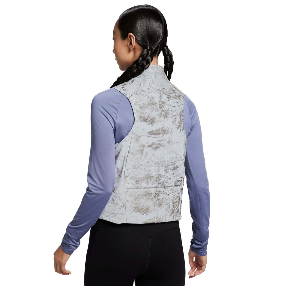 Back view of a model wearing the Nike Women's Therma-FIT ADV Reflective Running Vest in the Vast Grey/Black colourway. (8756535394466)