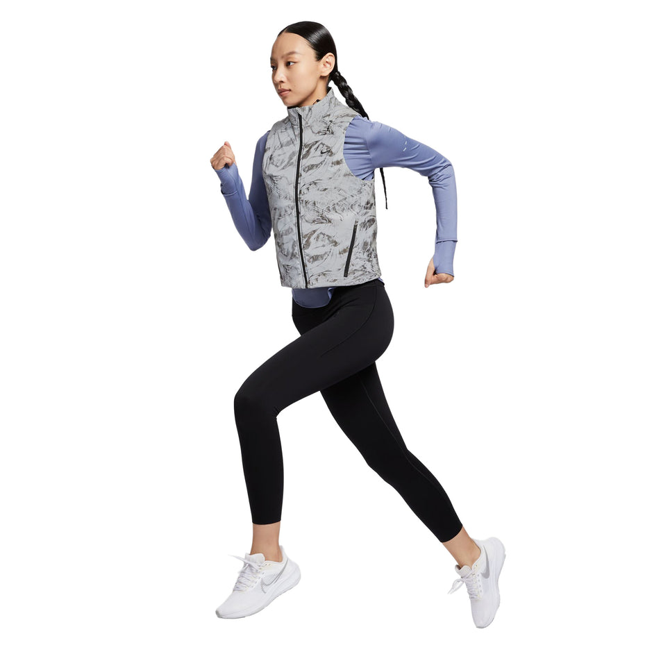 Angled view of a model wearing the Nike Women's Therma-FIT ADV Reflective Running Vest in the Vast Grey/Black colourway. (8756535394466)