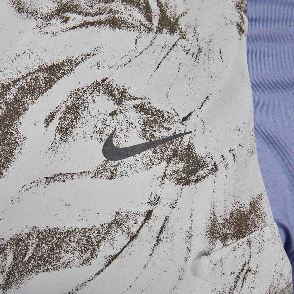 Close-up view of the Nike Swoosh on the Nike Women's Therma-FIT ADV Reflective Running Vest in the Vast Grey/Black colourway. (8756535394466)