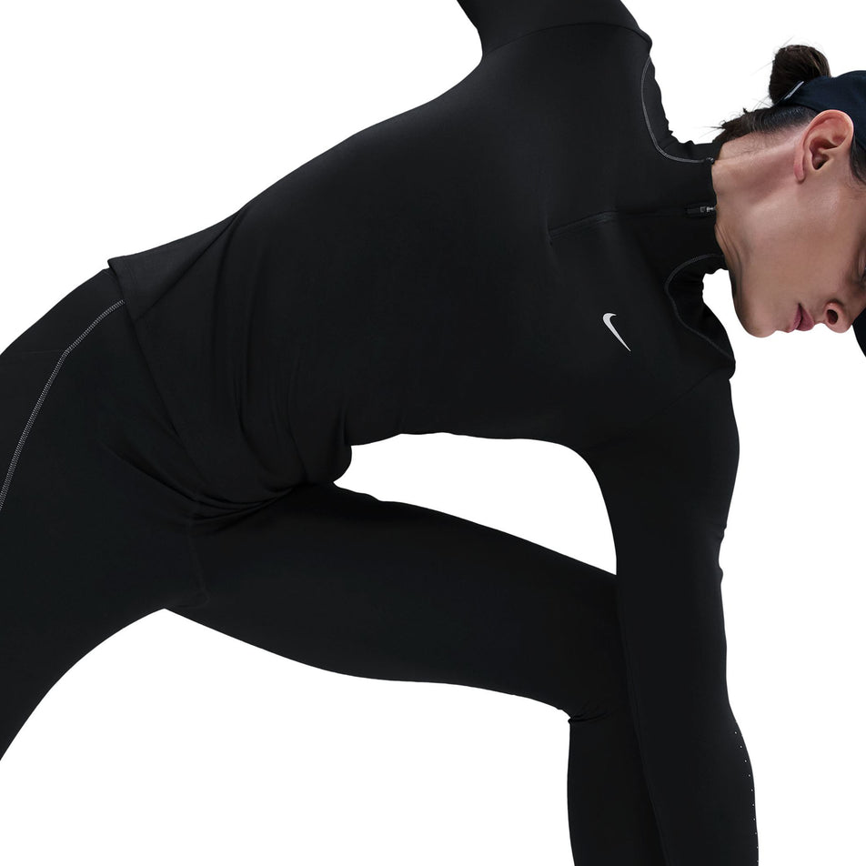 Angled view of a model wearing the Nike Women's Swift Therma-FIT ADV 1/4-Zip Running Top in the Black/Reflective Silver colourway. (8756532904098)