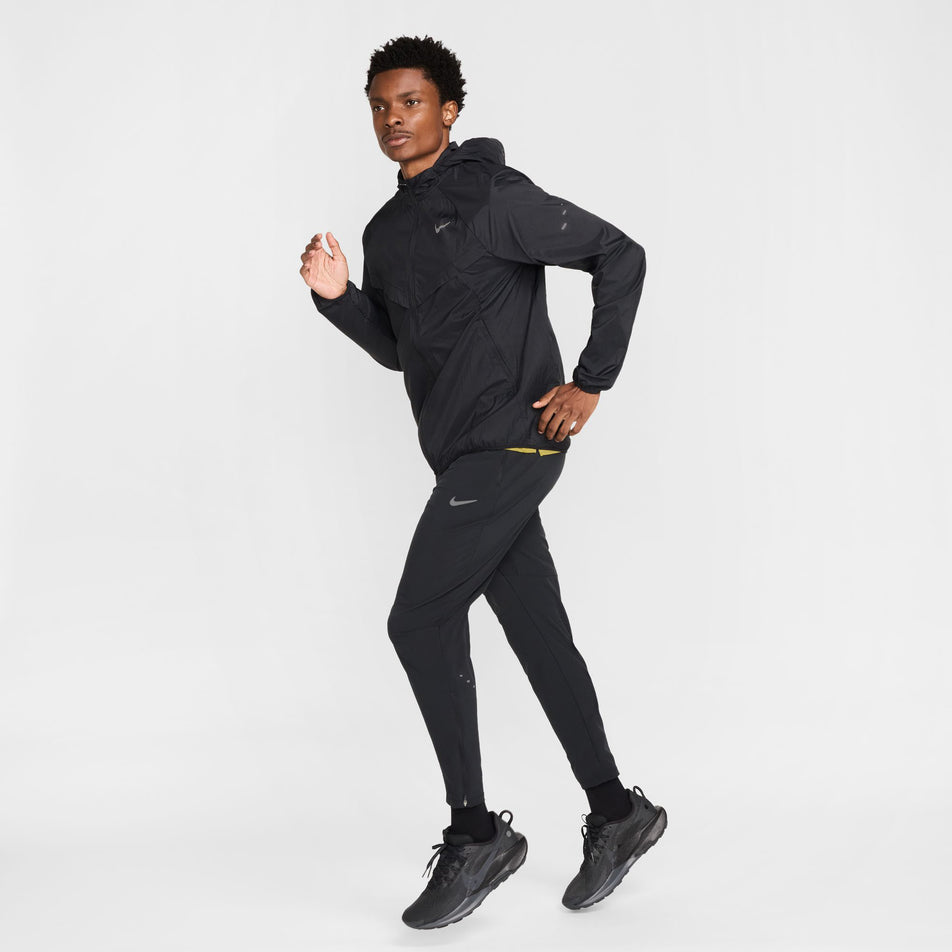 Angled view of a model wearing the Nike Men's Stride Dri-FIT Woven Running Pants in the Black/Reflective Silver colourway. (8778202644642)
