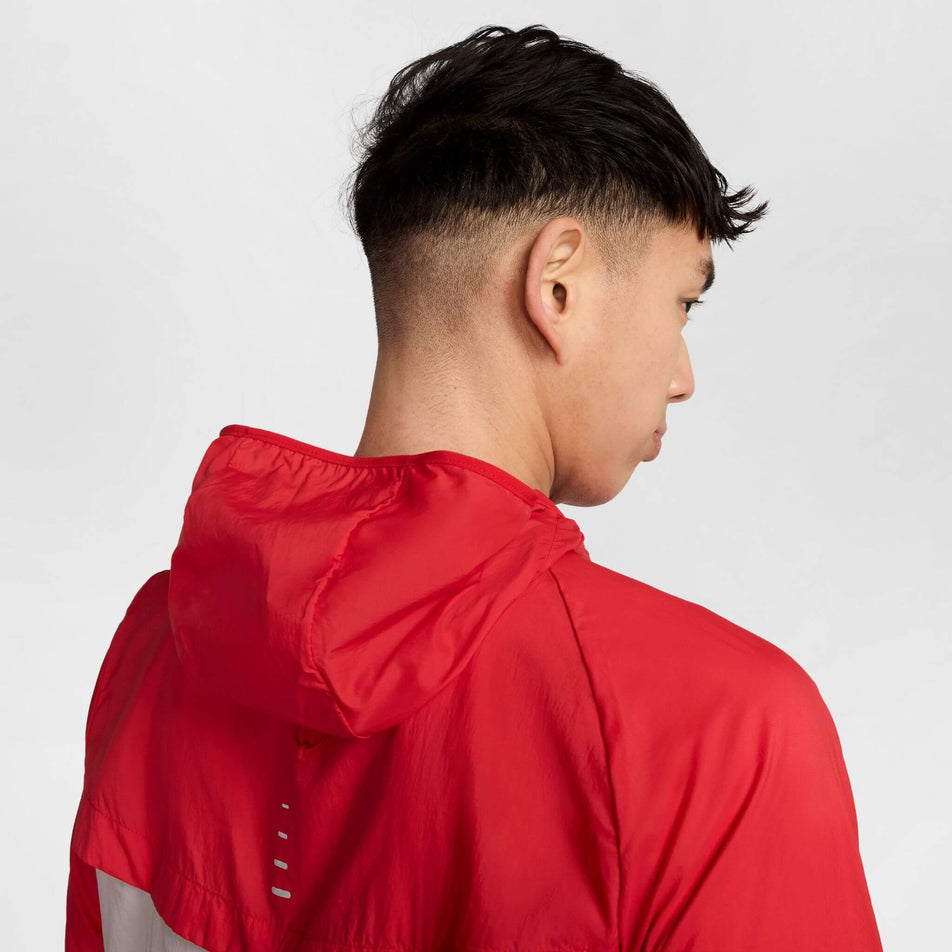 Close-up back view of a model wearing a Nike Men's Stride Repel UV Running Jacket in the University Red/Reflective Silver colourway. (8591132655778)