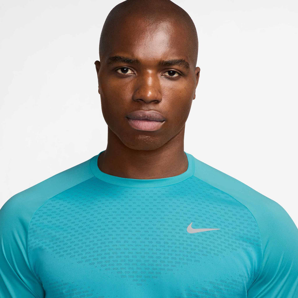 Close up view of the chest area of the Nike Men's Stride Dri-FIT ADV Short-Sleeve Running Top in the Dusty Cactus/Reflective Silver colourway. (8562852823202)