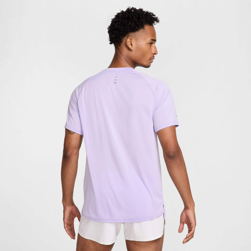 Back view of a model wearing the Nike Men's Stride Dri-FIT ADV Short-Sleeve Running Top in the Hydrangeas/Reflective Silv colourway. Model is also wearing shorts. (8620701089954)