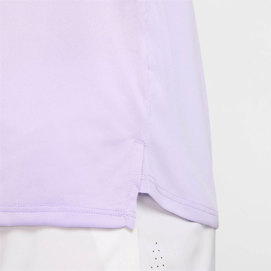 Close-up front view of the detail on the left hem of the Nike Men's Stride Dri-FIT ADV Short-Sleeve Running Top in the Hydrangeas/Reflective Silv colourway. Top is being worn by a model. (8620701089954)