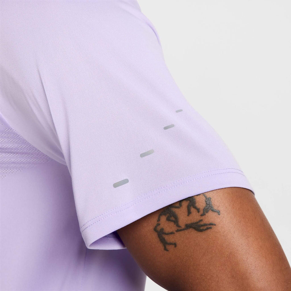 Close-up front view of the detail on the left sleeve of the Nike Men's Stride Dri-FIT ADV Short-Sleeve Running Top in the Hydrangeas/Reflective Silv colourway. Top is being worn by a model. (8620701089954)