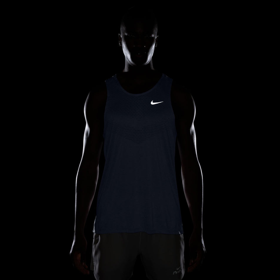 The reflective Nike Swoosh on the front of the Nike Men's Stride Dri-FIT ADV Running Tank Top in the Ghost/Heather/Reflective Silver colourway. (8710807388322)