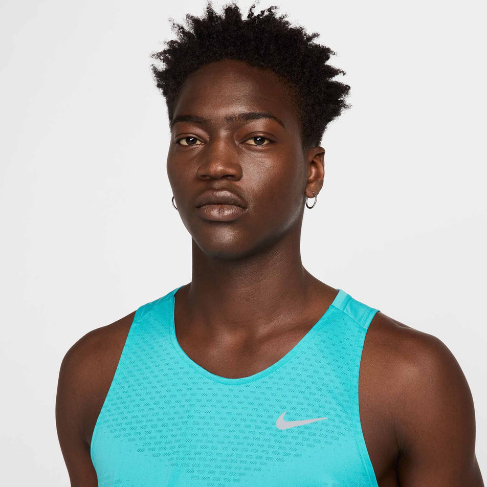 Close-up view of chest design of the Nike Men's Stride Dri-FIT ADV Running Tank Top in the Dusty Cactus/Reflective Silver colourway. (8563458703522)