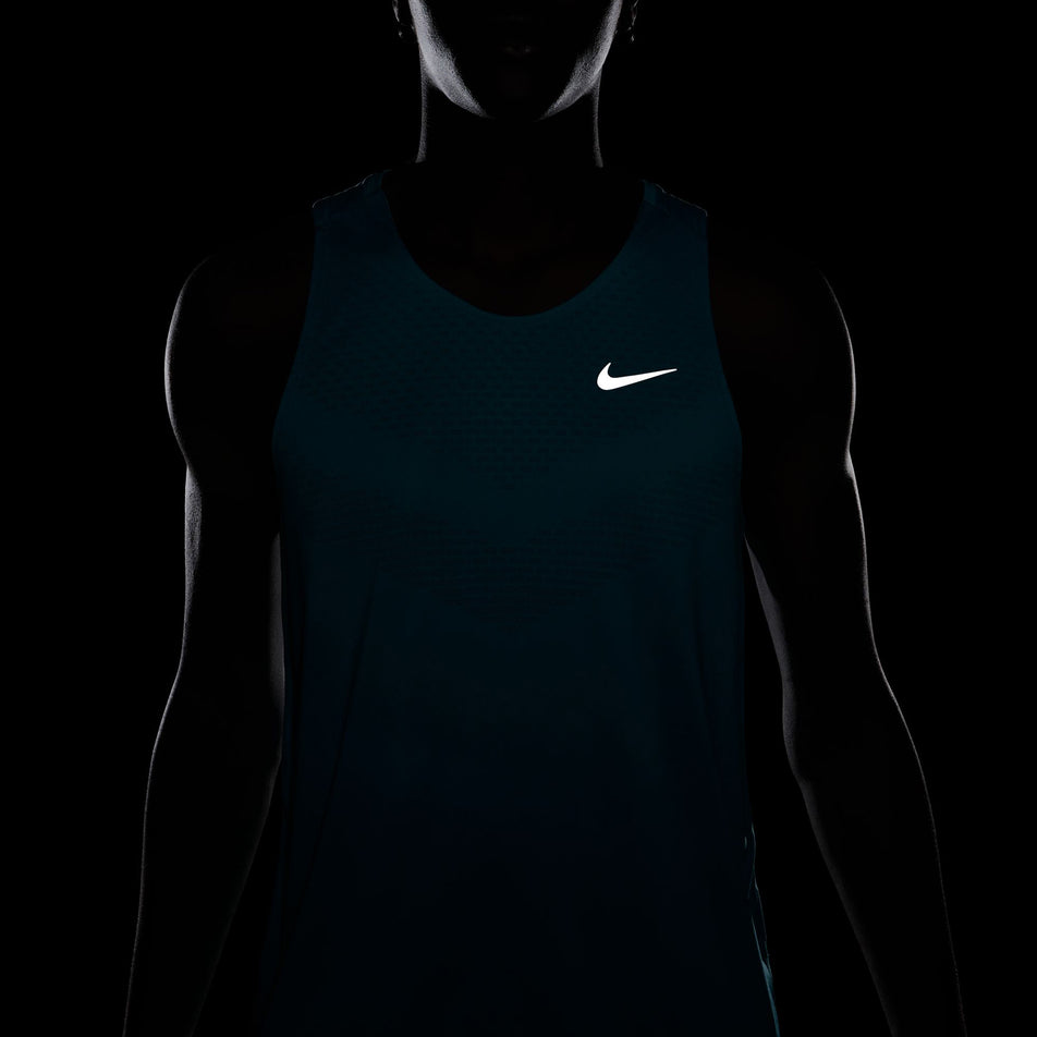 The reflective Nike SWOOSH on the front of the Nike Men's Stride Dri-FIT ADV Running Tank Top in the Dusty Cactus/Reflective Silver colourway. (8563458703522)