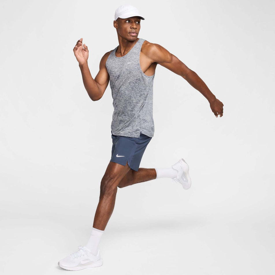 Side view of a model wearing the Nike Men's Stride Dri-FIT ADV Running Tank Top in the Thunder Blue/Heather/Reflective Silver colourway.(8620703940770)