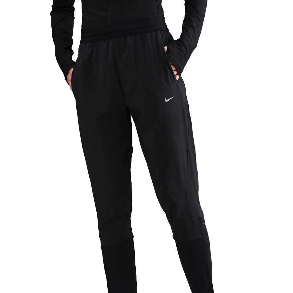 Front view of a model wearing the Nike Women's Dri-FIT Mid-Rise Running Pants in the Black/Reflective Silver colourway. (8732466151586)