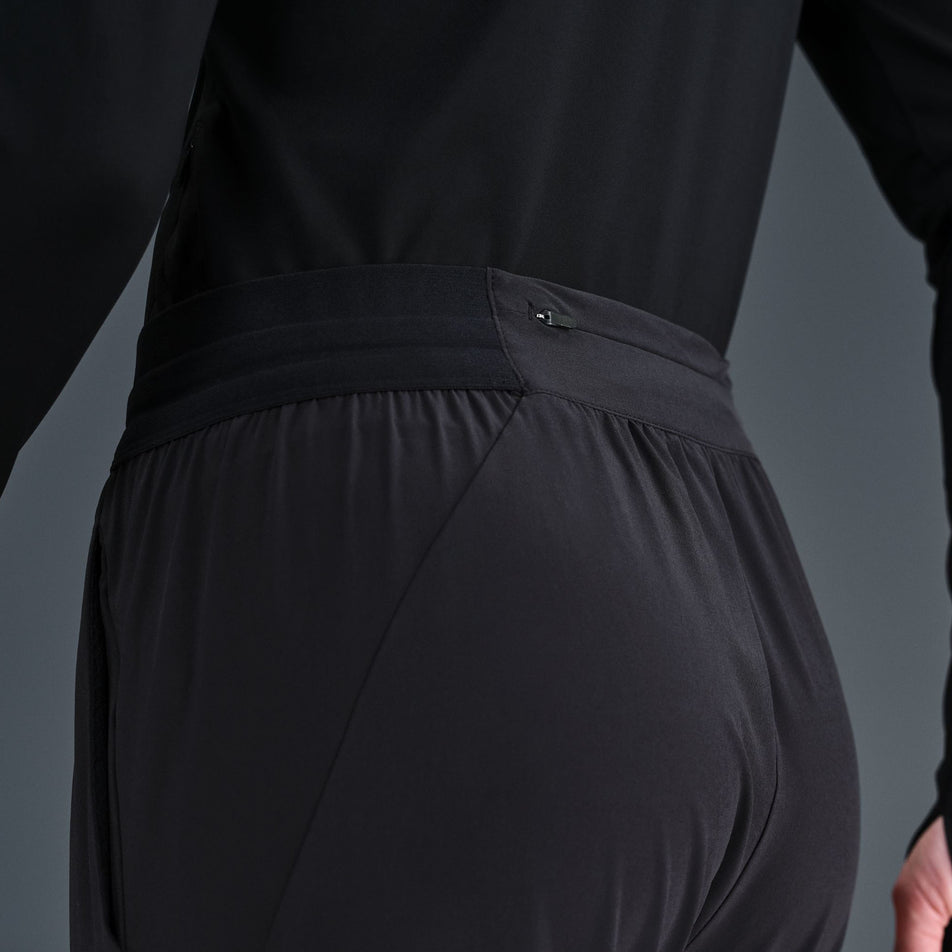 Close-up view of the zip pocket on the back of the Nike Women's Dri-FIT Mid-Rise Running Pants in the Black/Reflective Silver colourway.(8732466151586)