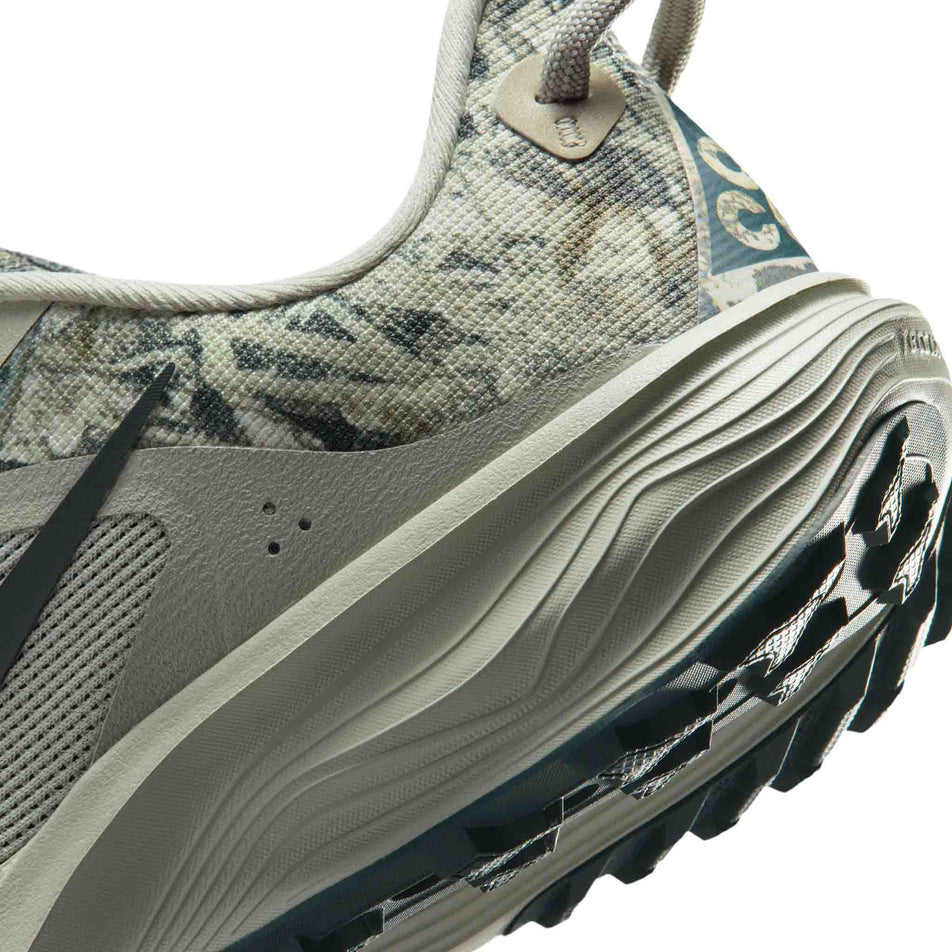 Close-up view of the rearfoot section of the left shoe from a pair of Nike Women's ACG Pegasus Trail Running Shoes in the Spruce Fog/Black Spruce-Sea Glass colourway.