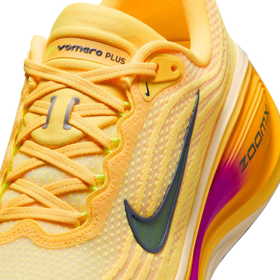 Close-up view of the upper of the left shoe from a pair of Nike Men's Vomero Plus Road Running Shoes in the Citron Pulse/Blue Void-Alabaster colourway.