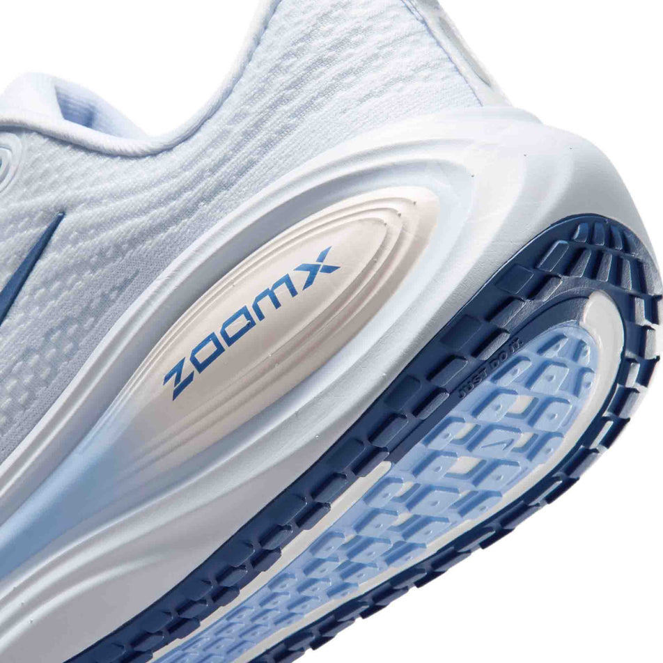 Close-up view of the rearfoot section of the left shoe from a pair of Nike Women's Vomero Plus Road Running Shoes in the White/Mystic Navy-Aluminum-Football Grey colourway.