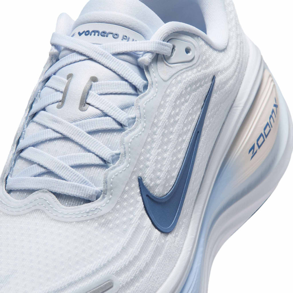 Close-up view of the upper of the left shoe from a pair of Nike Women's Vomero Plus Road Running Shoes in the White/Mystic Navy-Aluminum-Football Grey colourway.
