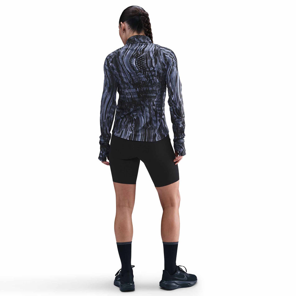 Back view of a model wearing the Nike Women's Swift Dri-FIT UV 1/2-Zip Printed Running Top in the World Indigo/Reflective Silver colourway. (8782446231714)
