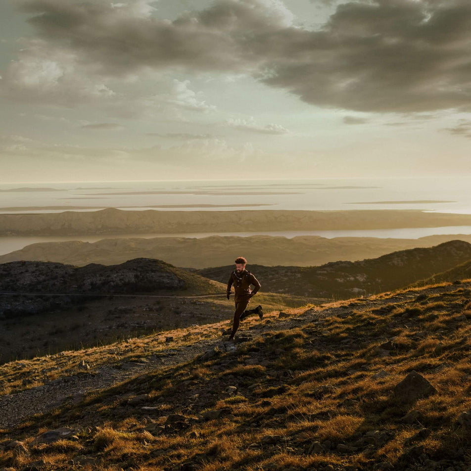 A runner running across a trail.